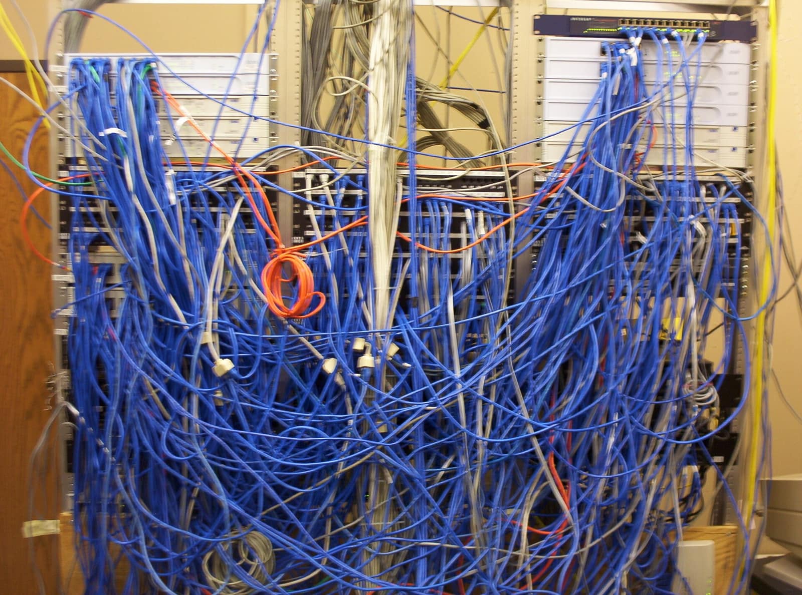 A cable closet with hundreds of blue patch cables hanging in loops across the switches