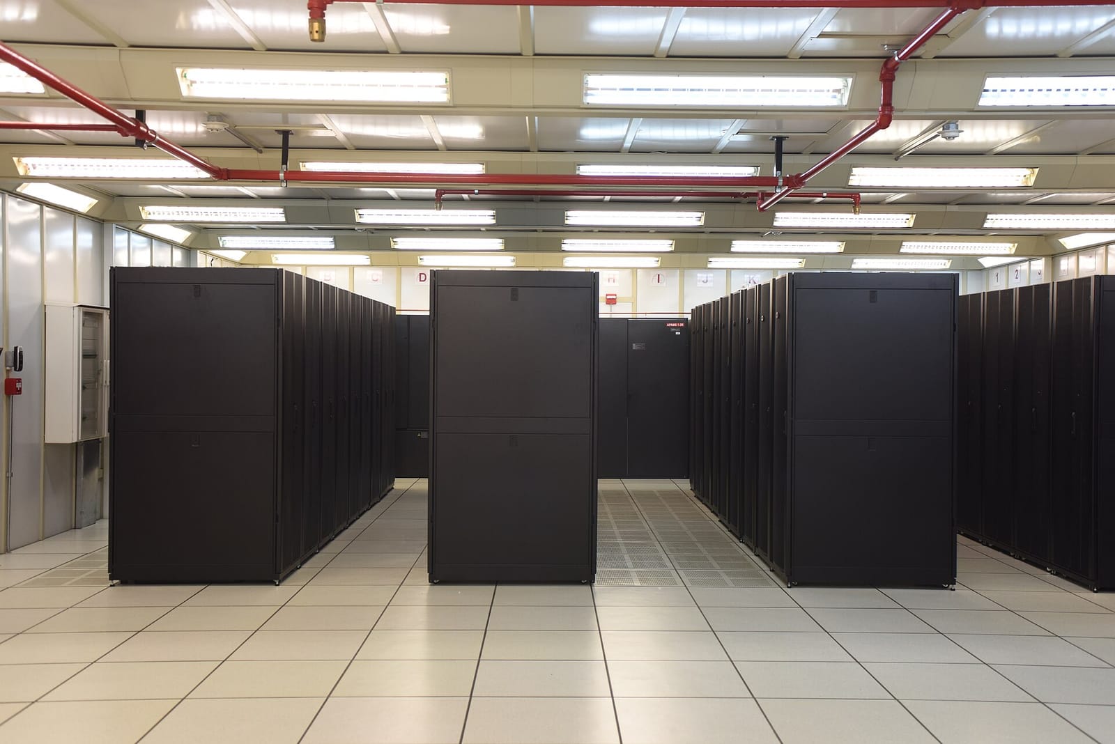 A data centre hall with rows of black server cabinets on a raised floor